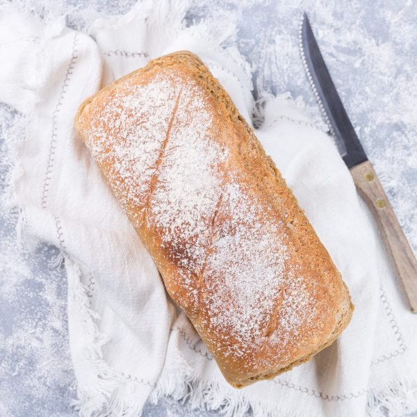 Loaf of homemade no knead sandwich bread with knife, ready to eat, top view, square format
